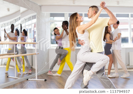 Young man and woman practicing salsa dance in pair in training hall 113794937