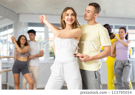 Young adult couple dancing playful bachata during group class 113795054