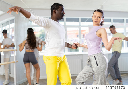 Woman dances incendiary boogie woogie with African man partner during choreography lesson 113795170