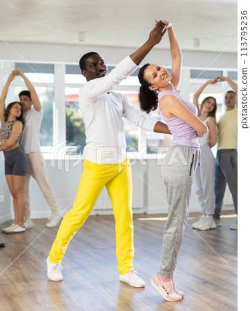 Woman dances incendiary tango with African man partner during choreography lesson Woman dances incendiary tango with African man partner during choreography lesson 113795236