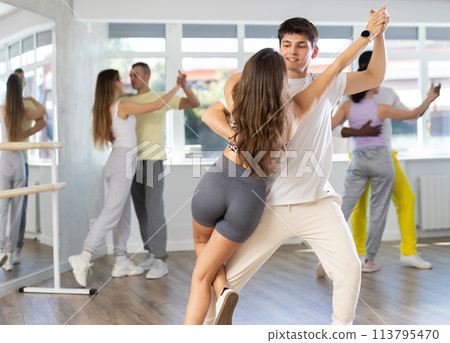 Smiling young woman and man in sportswear learn to dance couples latin dance, energetic and fast tango in dance salon 113795470