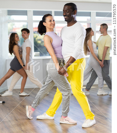 Beautiful young woman at dance salon with her african american partner dancing tango 113795570