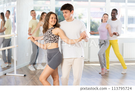 Young man and woman practicing salsa dance in pair in training hall 113795724