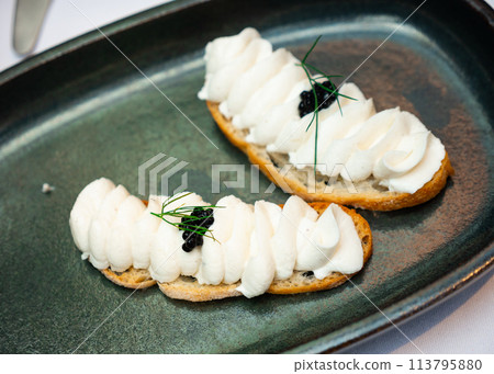 Fish butter and caviar appetizer served on black plate 113795880