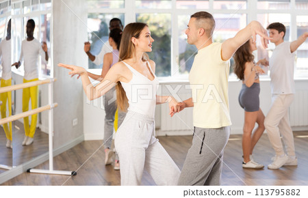 Young woman dances incendiary boogie woogie with man partner during choreography lesson 113795882