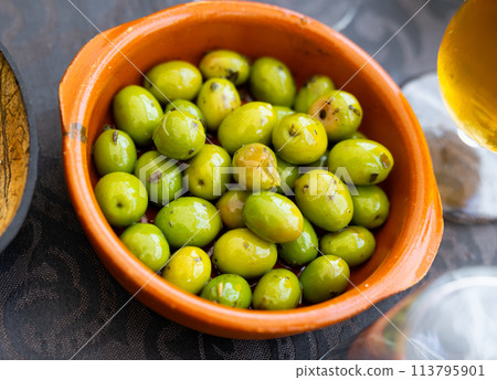 Typical spanish tapas is green pickled olives with pits 113795901