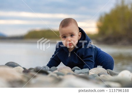 Caucasian Baby Boy playing outside with rocks by river. 113796188
