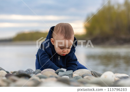 Caucasian Baby Boy playing outside with rocks by river. 113796283