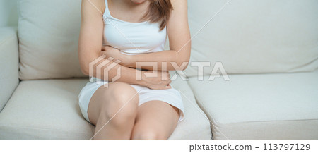woman having abdomen ache due to Stomach pain, digestion with constipation or Diarrhea from food poisoning, female problem and Endometriosis, Hysterectomy, Stomachache and Menstrual on sofa at home 113797129