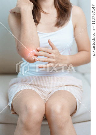 Arthritis and Muscle Pain Relief Cream concept. Woman having elbow ache at home, muscle pain due to lateral epicondylitis or tennis elbow. injury, Health and medical concept 113797147