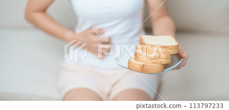 Gluten intolerance, Gluten free and celiac disease or wheat allergy concept. woman hold Bread and having abdominal pain after eat gluten. stomach ache, Nausea, Bloating, Gas, Diarrhea and Skin rash 113797233