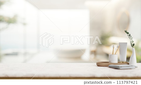 A toothpaste, toothbrushes, a towel on a white tabletop in a contemporary bathroom with a bathtub. A toothpaste, toothbrushes, a towel on a white tabletop in a contemporary bathroom with a bathtub. 113797421