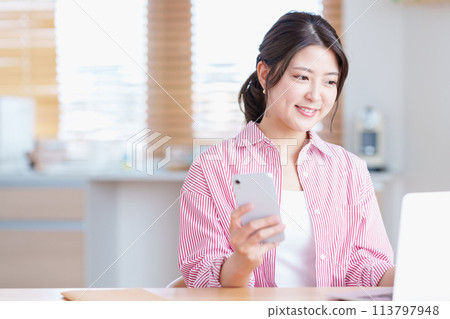 一名年輕女子在客廳工作。 113797948