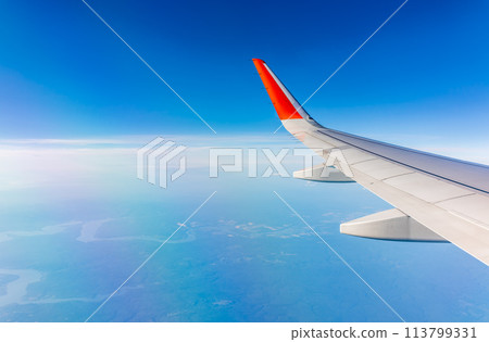 Aerial view from airplane window above green ground. View from the airplane window with beautiful clouds at sunrise 113799331