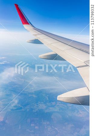 View from the airplane window at a beautiful cloudy sky and the airplane wing 113799332