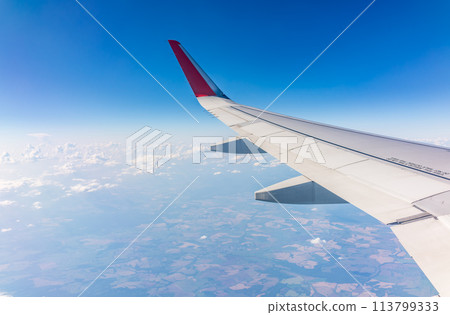View from the airplane window at a beautiful cloudy sky and the airplane wing View from the airplane window at a beautiful cloudy sky and the airplane wing 113799333