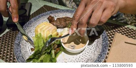 Beef New York strip loin steak or sirloin steak served with potatoes, and mushroom sauce and salad on plate Beef New York strip loin steak or sirloin steak served with potatoes, and mushroom sauce and salad on plate 113800593