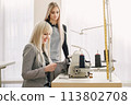 Two young seamstresses sitting on the sewing machine in her workshop 113802708