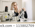Young seamstress sitting on the sewing machine in her workshop 113802709