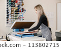 Young dressmaker standing in workshop near the bright wall with threads 113802715