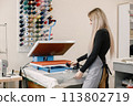 Young dressmaker standing in workshop near the bright wall with threads 113802719