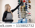 Female dressmaker standing in her workshop near the bright wall with threads 113802732