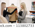 Female dressmaker measuring jacket on dummy to make recesses 113802733