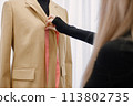 Female dressmaker measuring length on dummy to make recesses 113802735