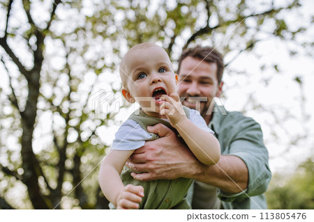 Father holding little baby, playing, having fun during warm spring day. Father's day concept. Father holding little baby, playing, having fun during warm spring day. Father's day concept. 113805476