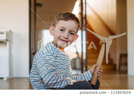 Boy holding wind turbine model. Concpet of renewable energy sustainable lifestyle for next generations. 113805659