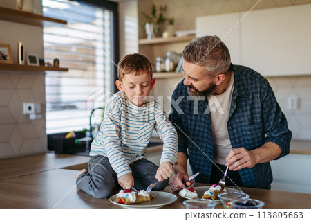 Boy filling pancake with fruit, sweets. Father spending time with son at home, making snack together, cooking. Fathers day concept. Boy filling pancake with fruit, sweets. Father spending time with son at home, making snack together, cooking. Fathers day concept. 113805663