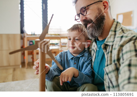Son and father holding wind turbine model. Concpet of renewable energy sustainable lifestyle for next generations. 113805691