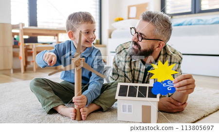 Father explaining renewable energy, teaching about sustainable lifestyle his young son. Playing with house with solar panels, wind turibine at home. Father explaining renewable energy, teaching about sustainable lifestyle his young son. Playing with house with solar panels, wind turibine at home. 113805697