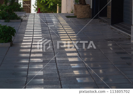 A pedestrian sidewalk made of granite tiles leads travelers out of darkness and into the light. Direction of movement in the right direction, hints from the Almighty, tests on the path of life 113805702