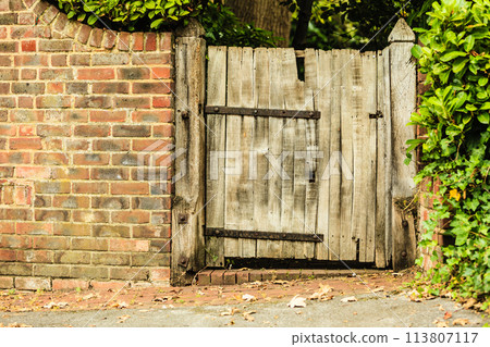 Rustic old wooden gate in brick wall 113807117