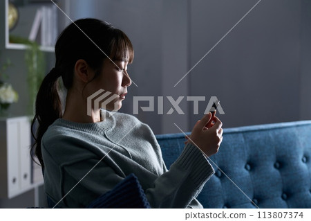 A depressed woman looking at a smartphone 113807374