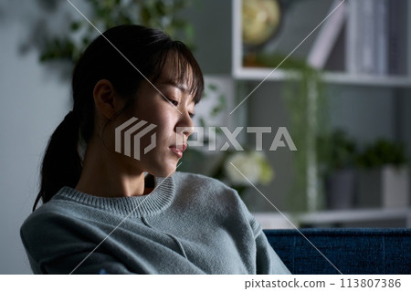 A woman thinking in a dark room 113807386