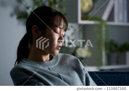 Woman closing her eyes in a dark room 113807388