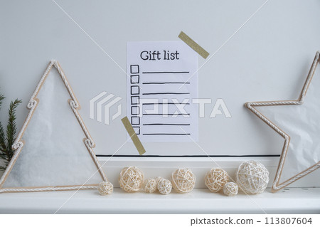 Holiday preparation paper note with GIFT LIST checklist text. Vision board wall with cozy minimalistic handmade new year Christmas decor Low key festive celebration Holiday preparation paper note with GIFT LIST checklist text. Vision board wall with cozy minimalistic handmade new year Christmas decor Low key festive celebration 113807604