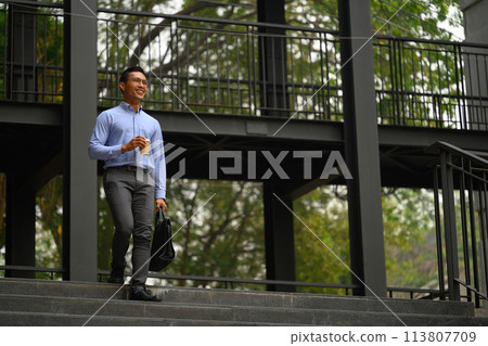 Confident smiling young businessman walking down the staircase outside his office Confident smiling young businessman walking down the staircase outside his office 113807709