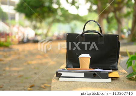 Closeup of briefcase, takeaway coffee cup and document on concrete bench. City life concept 113807710