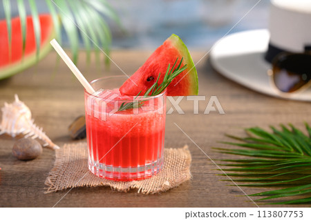 Freshly watermelon juice in glasses and palm leaf on wooden table. Refreshing summer drink concept 113807753