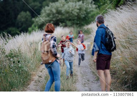 Young students having fun during biology field teaching class, running down the dirt path. Dedicated teachers during outdoor active education teaching about ecosystem, ecology. 113807861