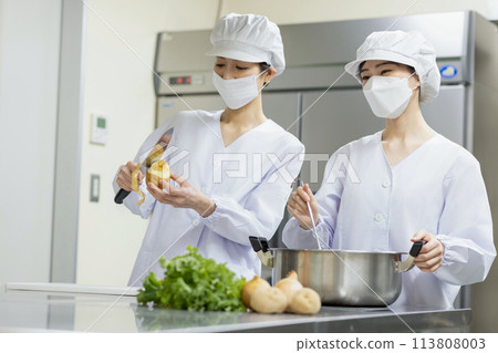 A woman wearing a lab coat and making a meal A woman wearing a lab coat and making a meal 113808003