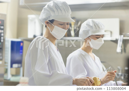 A woman wearing a lab coat and making a meal A woman wearing a lab coat and making a meal 113808004