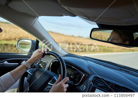 Inside view of woman driving car on countryside road 113808497