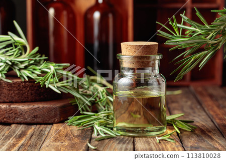 Rosemary essential oil or infusion on an old wooden table. Rosemary essential oil or infusion on an old wooden table. 113810028
