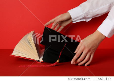 Graduate hat and books, on a red background. 113810142