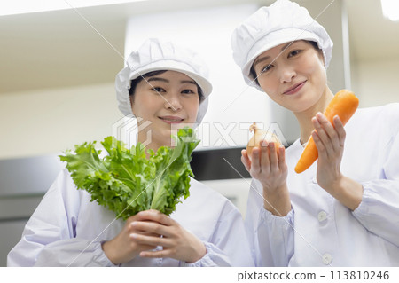 A woman wearing a lab coat and making a meal 113810246