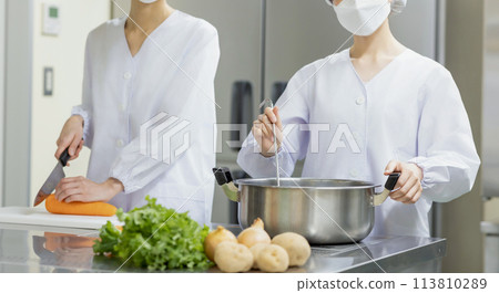 A woman wearing a lab coat and making a meal 113810289